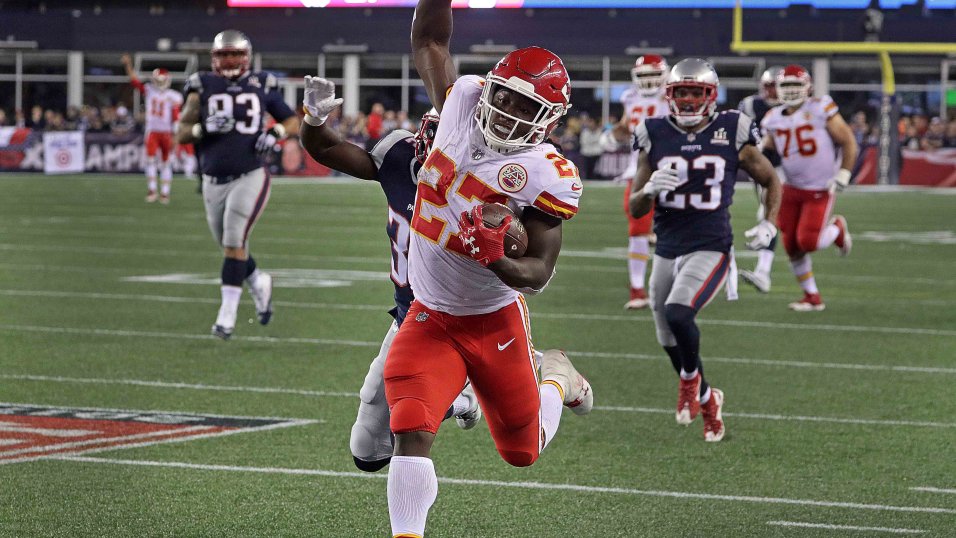 Kansas City Chiefs running back Kareem Hunt (27) gives a stiff arm to New  England Patriots defensive back Devin McCourty (32) as he runs for yardage  during the first half of an