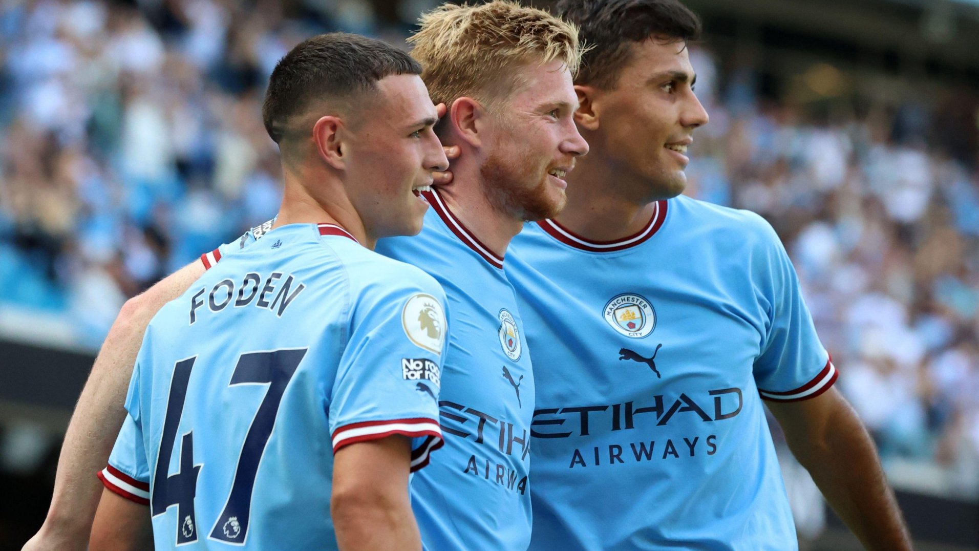  Rodri, Declan Rice, and Kevin De Bruyne are all pictured smiling while playing soccer for Manchester City.